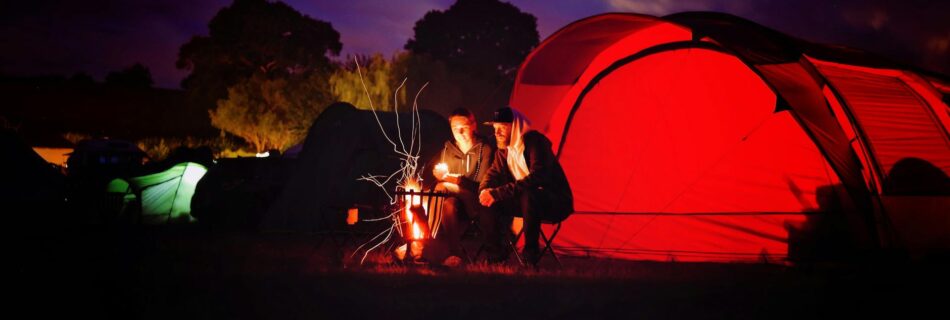 man and woman sitting beside bonfire during nigh time