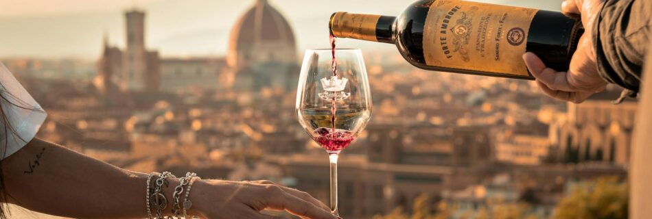 pouring wine to woman glass in sunlight and with town behind