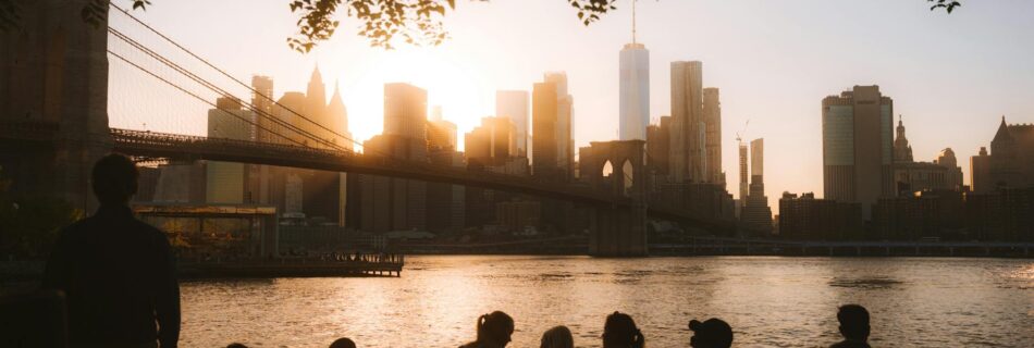 group looking at illuminated nyc downtown and brooklyn bridge at dusk