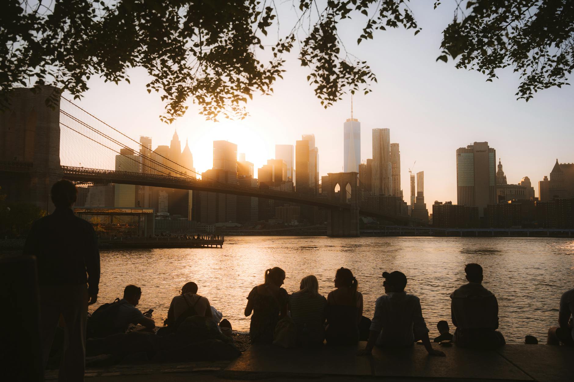 group looking at illuminated nyc downtown and brooklyn bridge at dusk