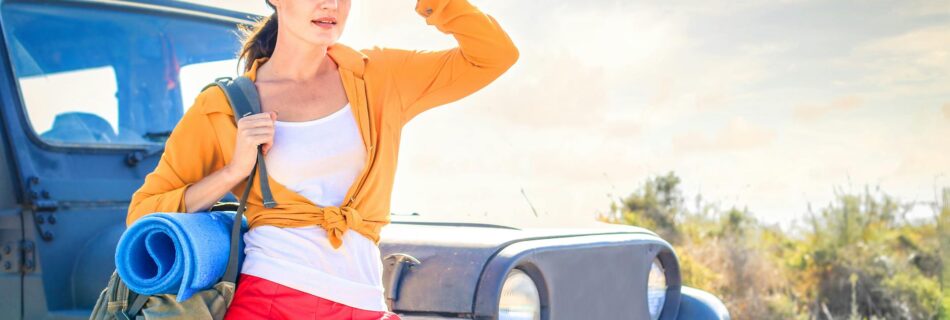 woman in yellow long sleeve leaning on blue car