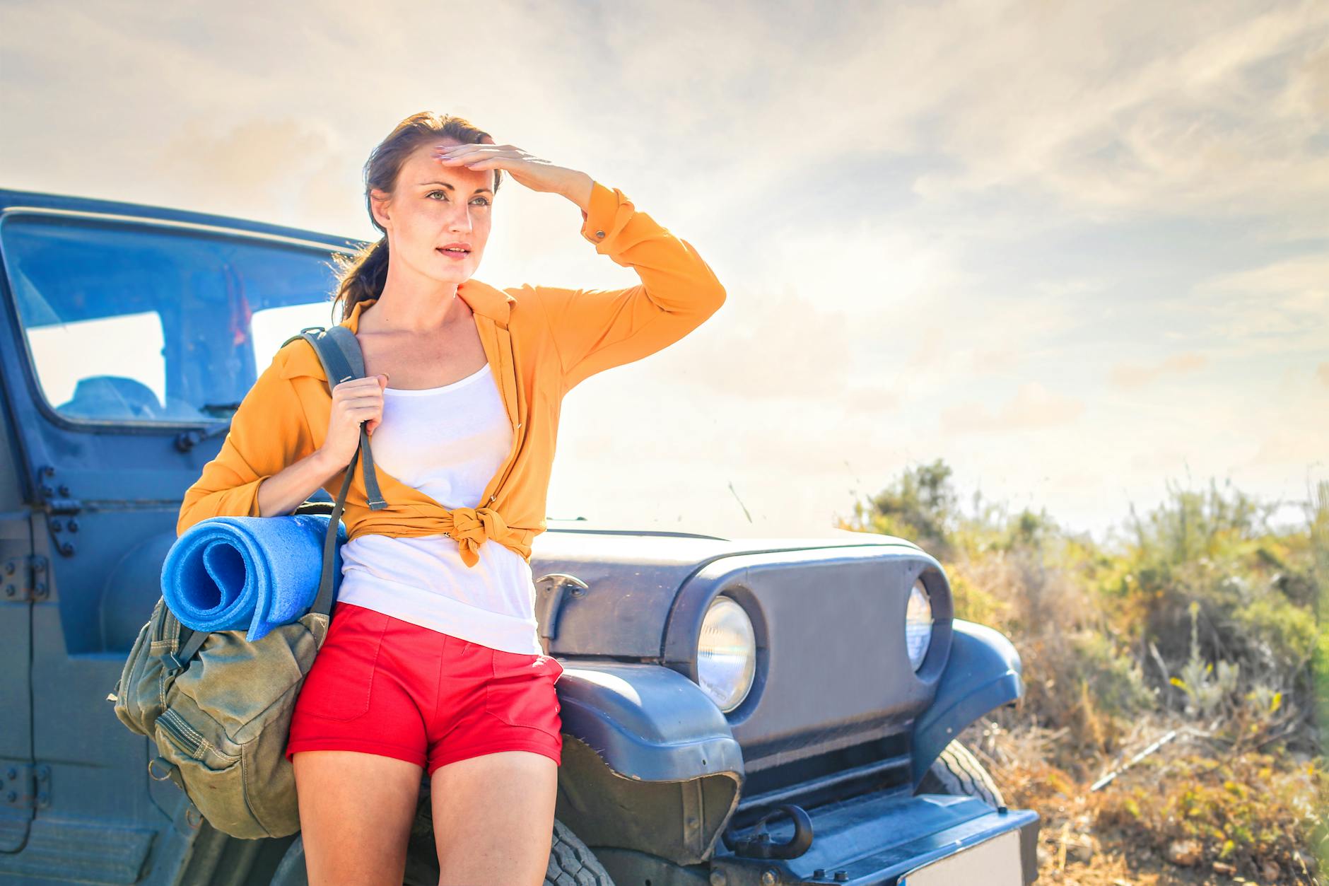 woman in yellow long sleeve leaning on blue car