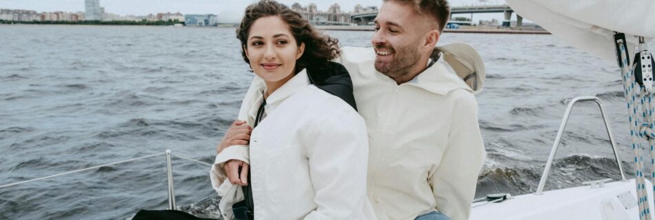 man in white suit jacket sitting beside woman in blue denim shorts on boat