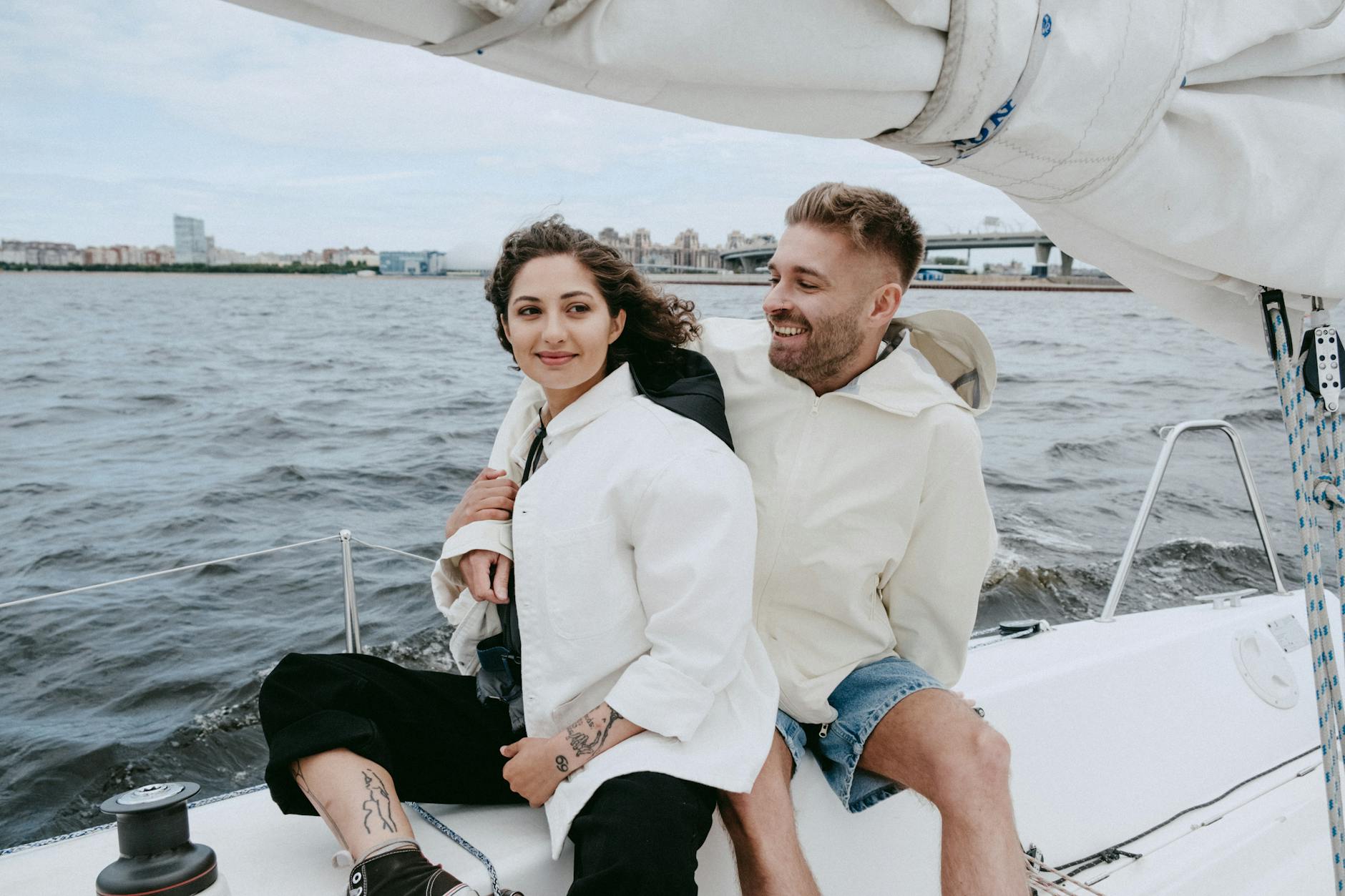 man in white suit jacket sitting beside woman in blue denim shorts on boat