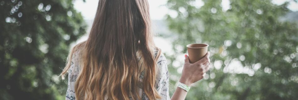 woman holding brown paper cup