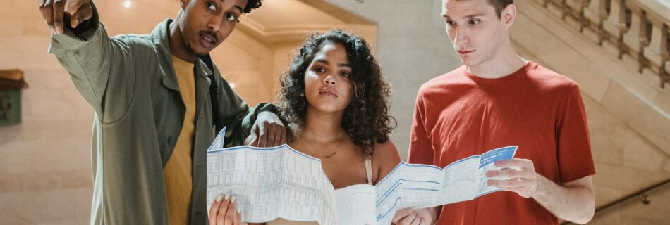 concentrated young multiethnic friends with map in railway station