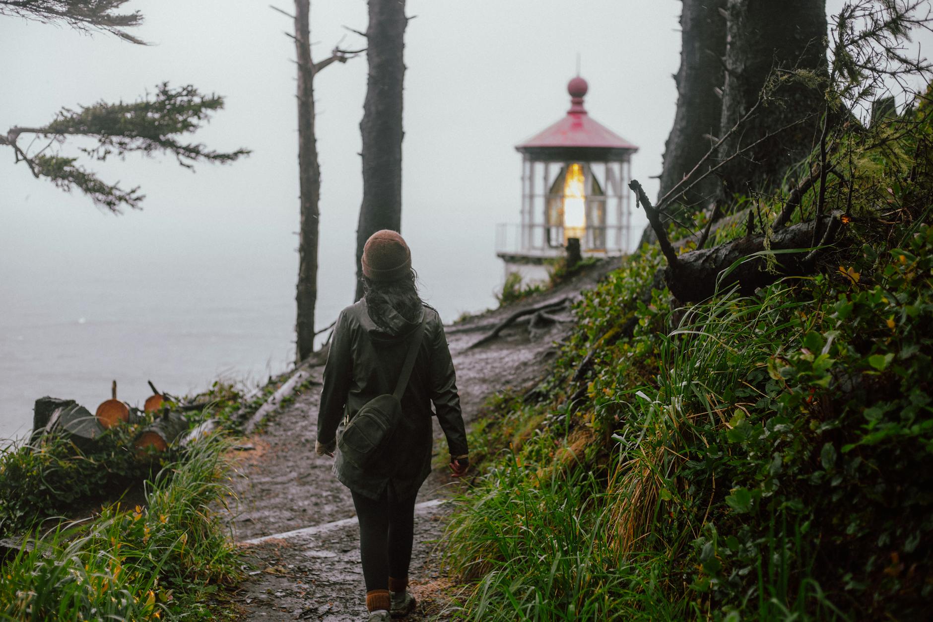 woman in green jacket walking on pathway near body of water