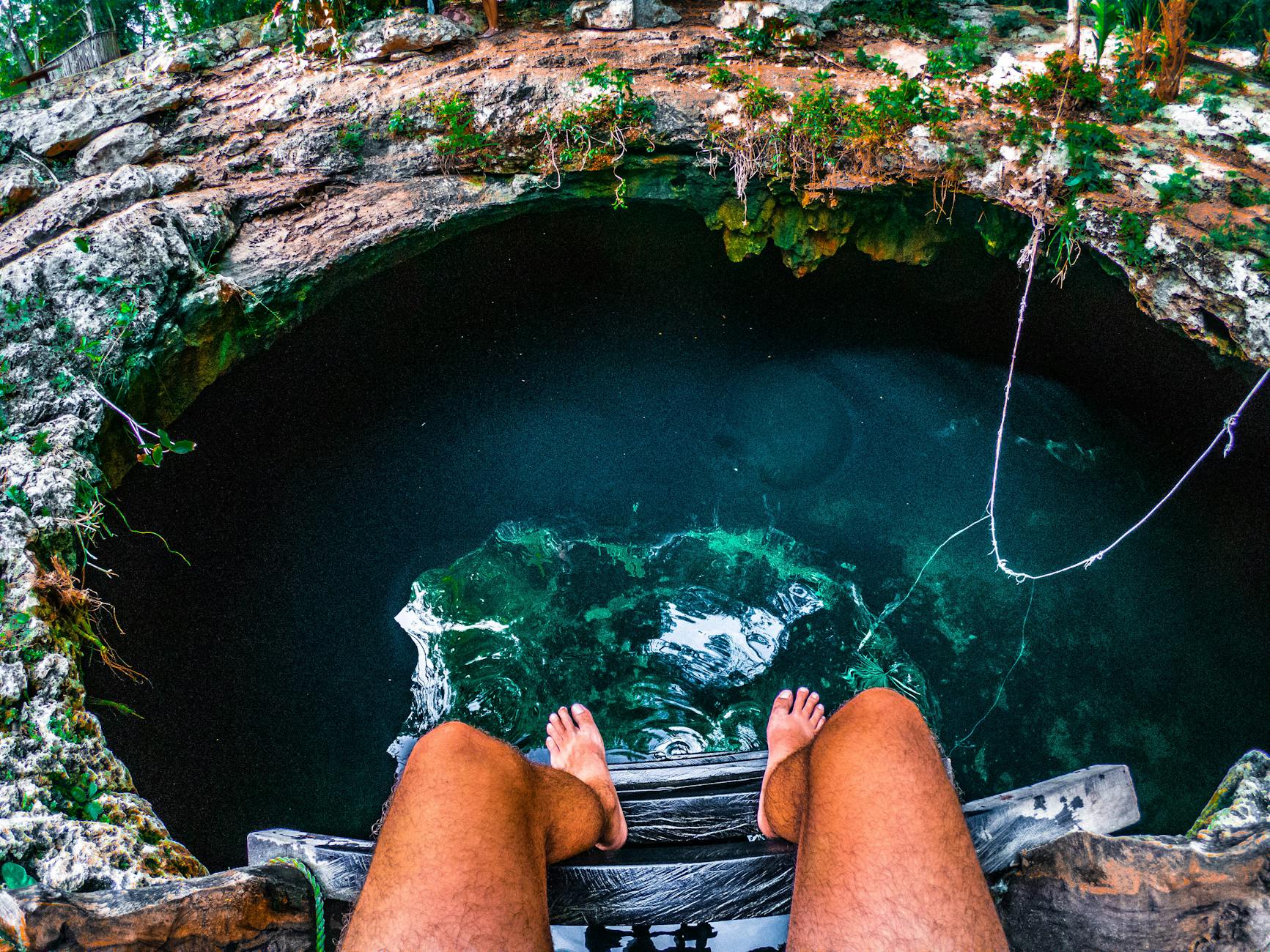 person sitting on a ladder with view of underground water