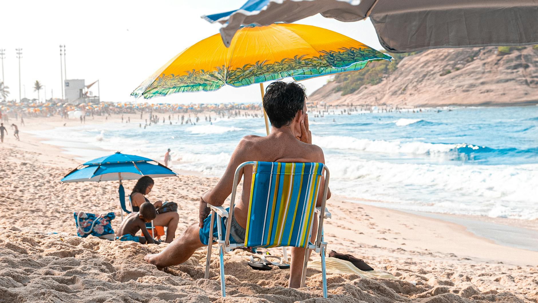man sitting on sunbed on beach