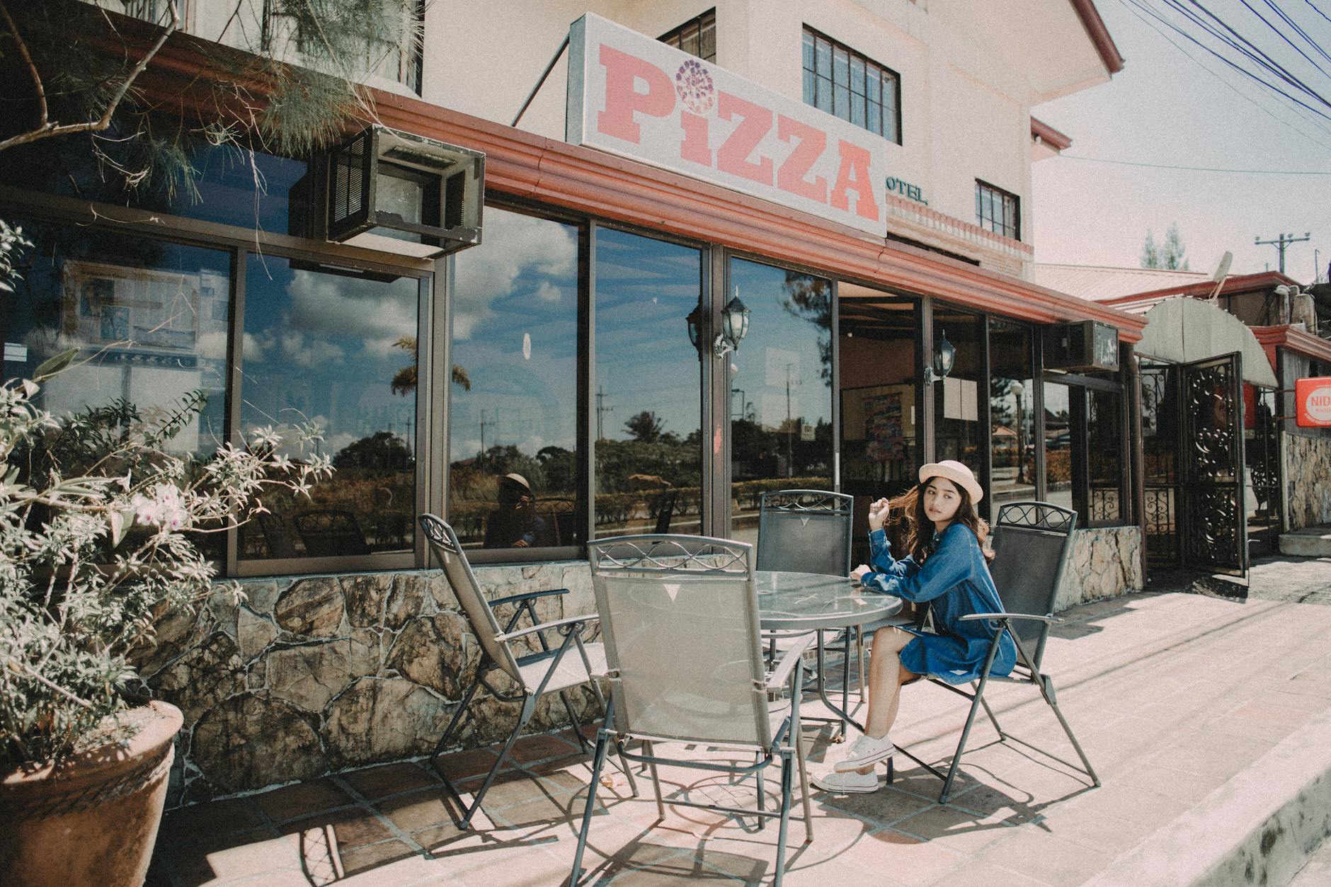woman sitting outside a pizza store