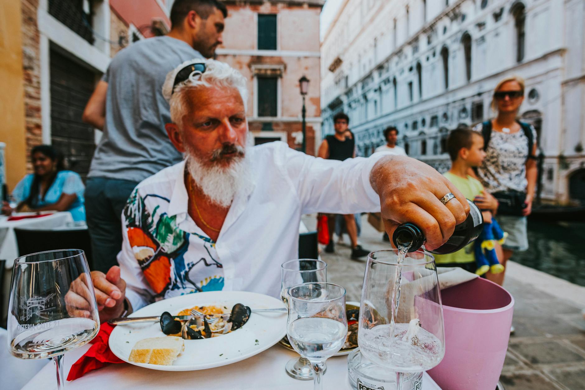 elderly bearded man pouring wine in restaurant