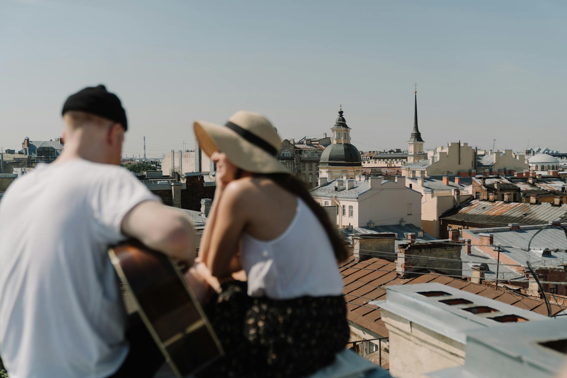 man in white tank top and brown hat standing on roof top