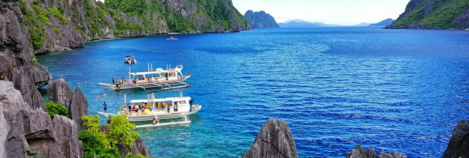 white boats on sea near the gray rock formation