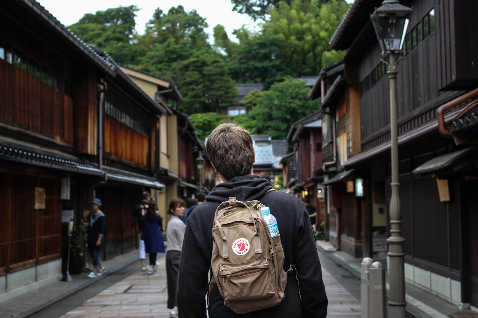 unrecognizable man with backpack strolling on street