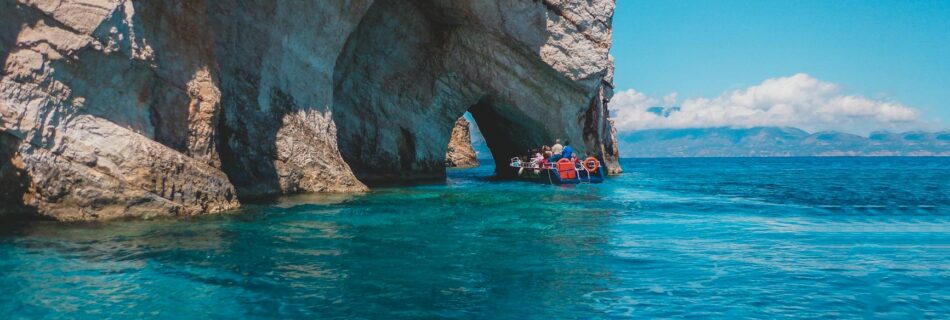 people riding on boat near the rock formation under the blue sky