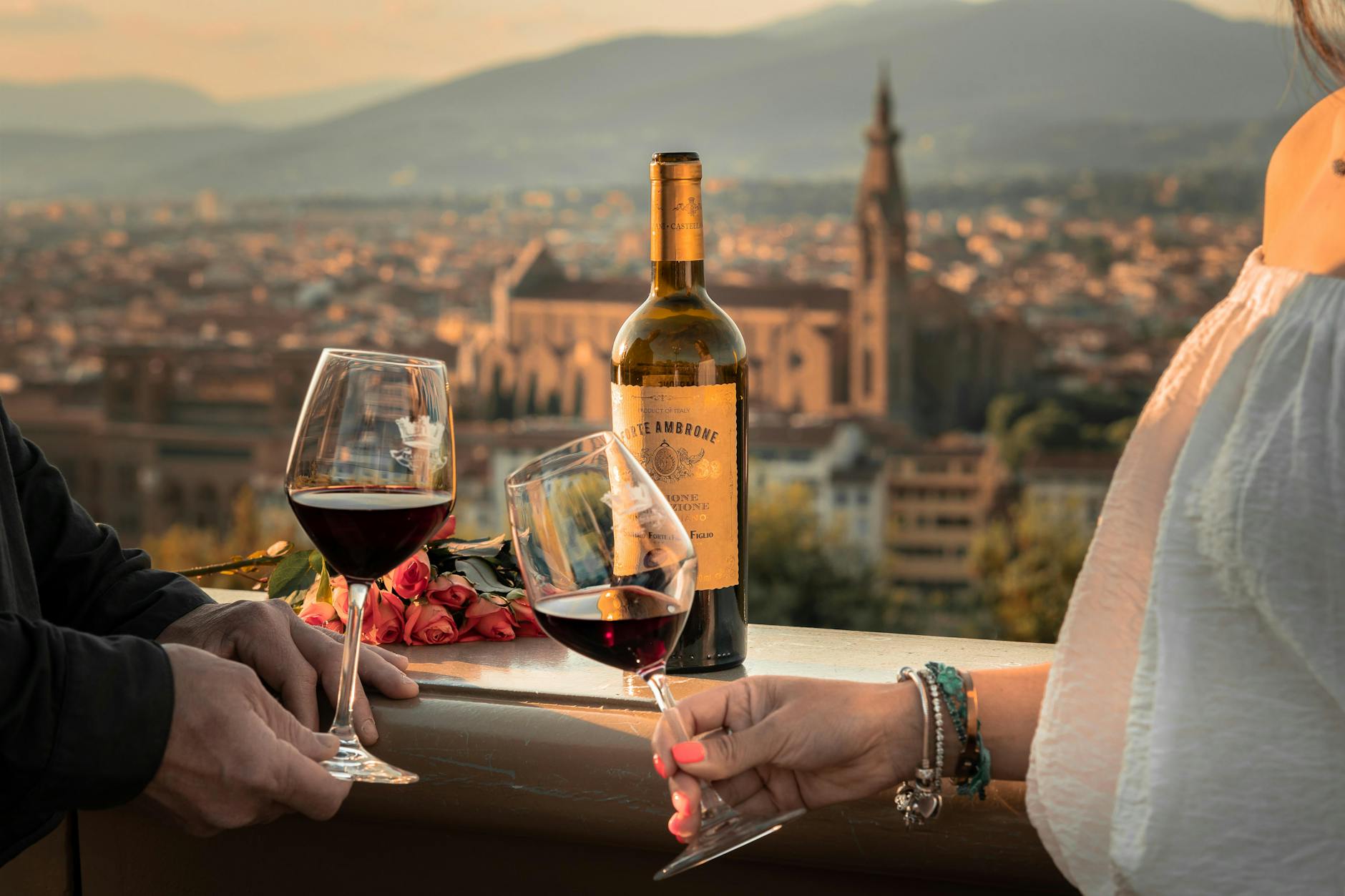 man and woman hands holding wine glasses in town in tuscany
